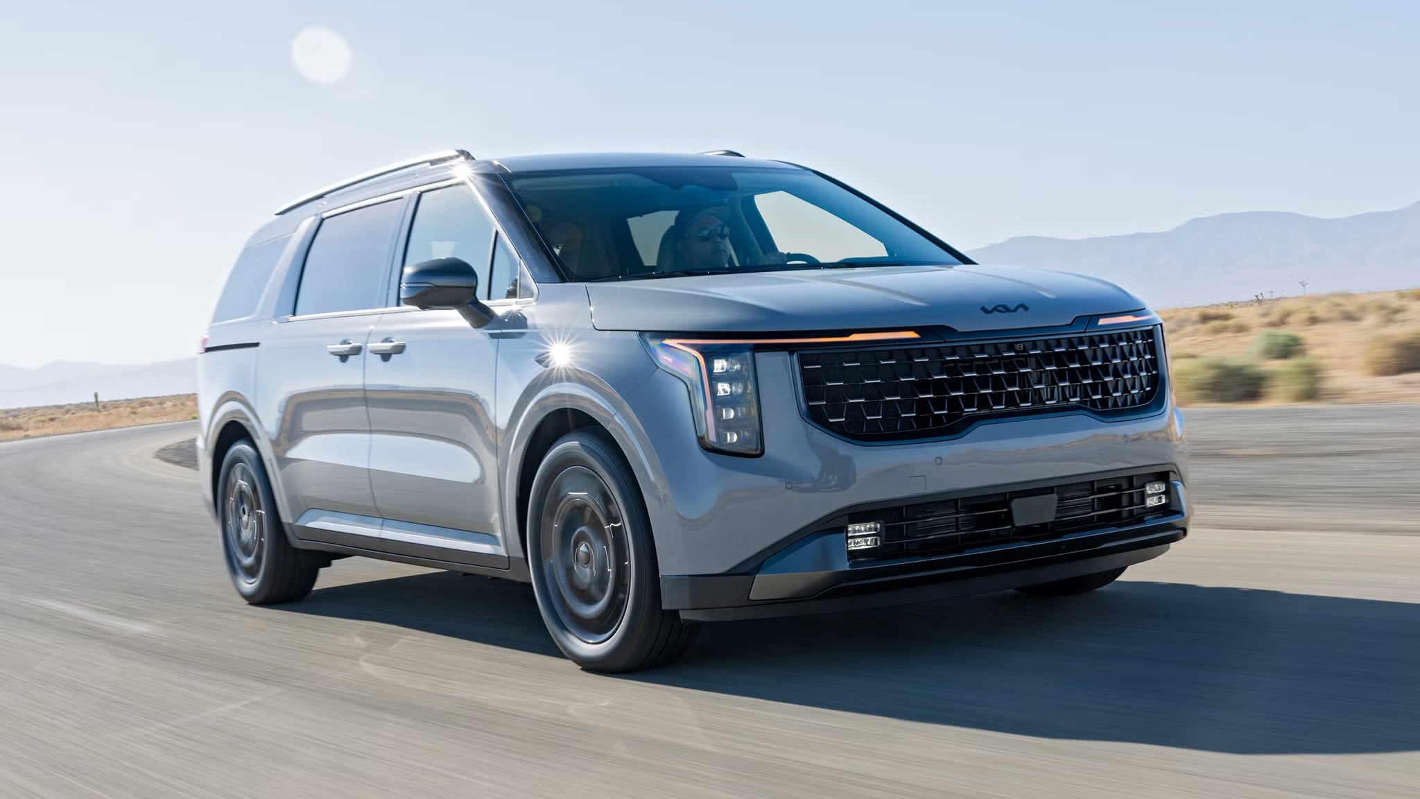 Gray Kia Carnival driving on an open road