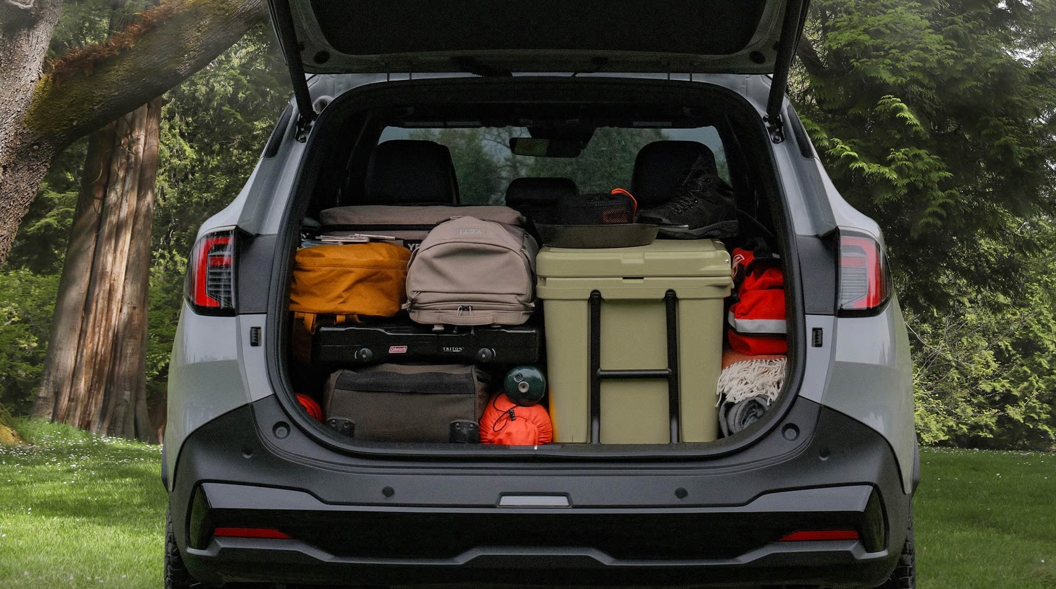 Open SUV cargo area packed with camping gear, including a cooler and backpacks.