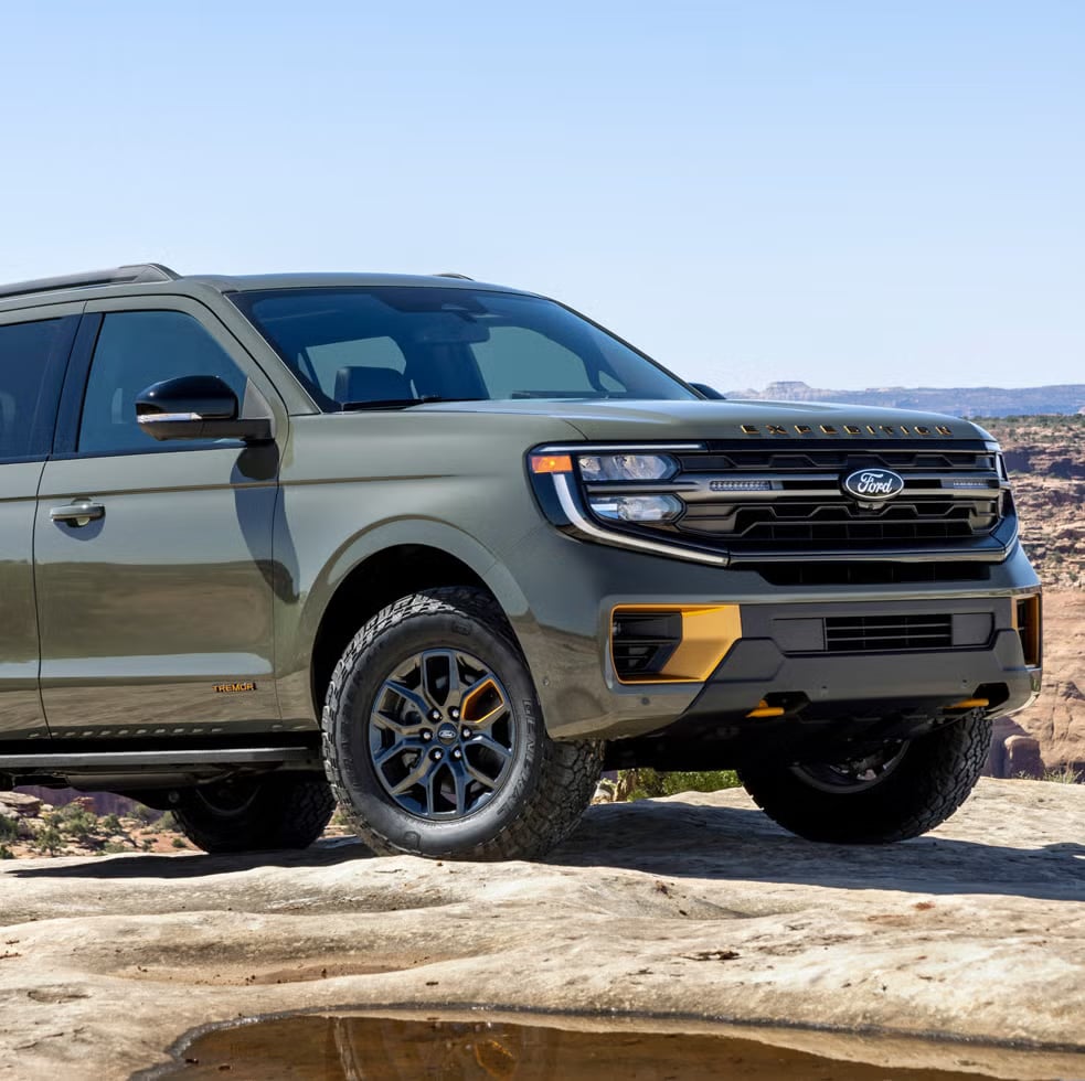 Olive green Ford Expedition Tremor SUV parked on slickrock in a sunny desert canyon.