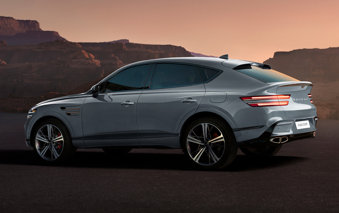 Side profile of a gray Genesis GV80 Coupe at sunset