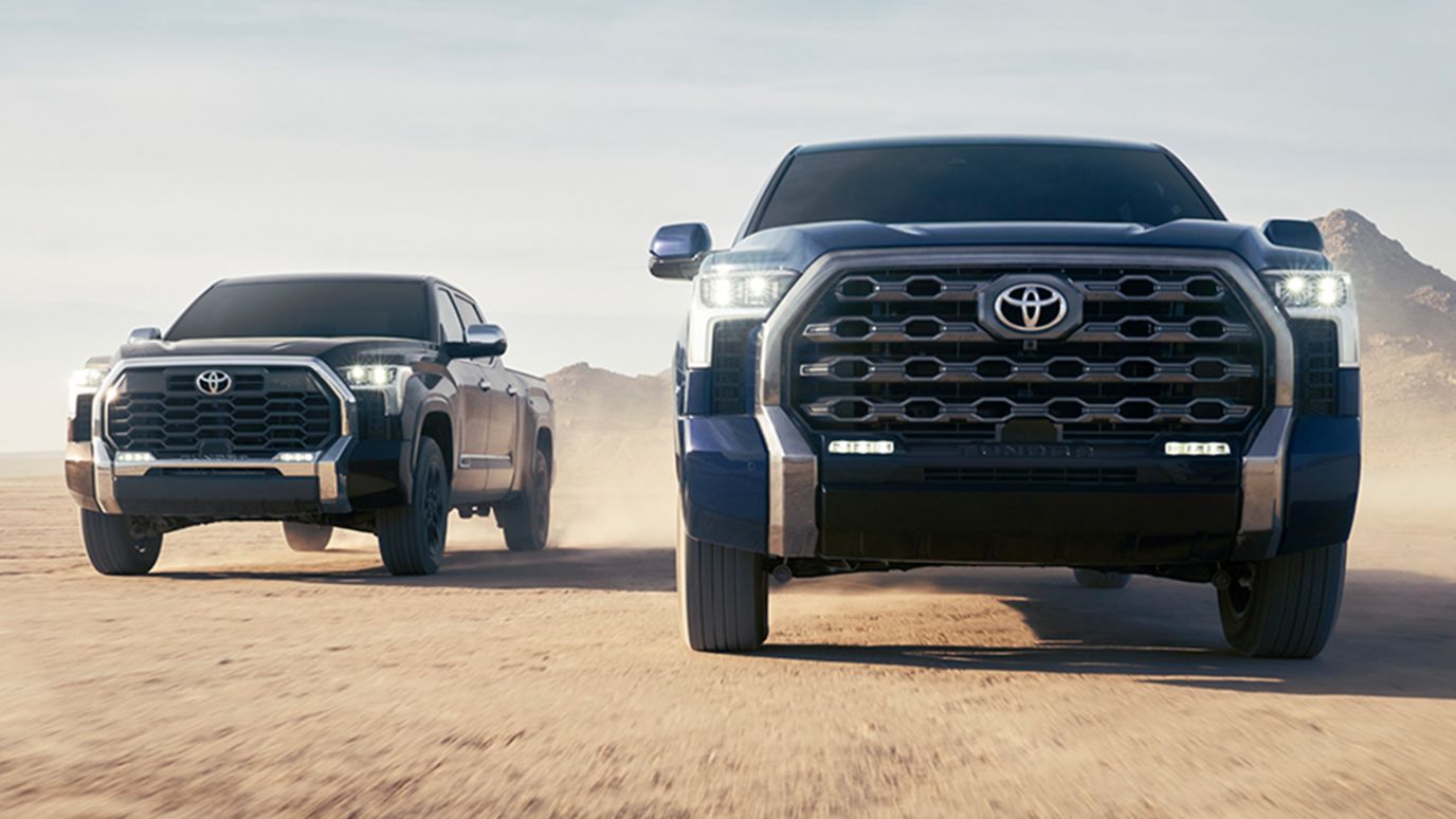 A front view of a blue and black Toyota Tundra driving off-road through the desert