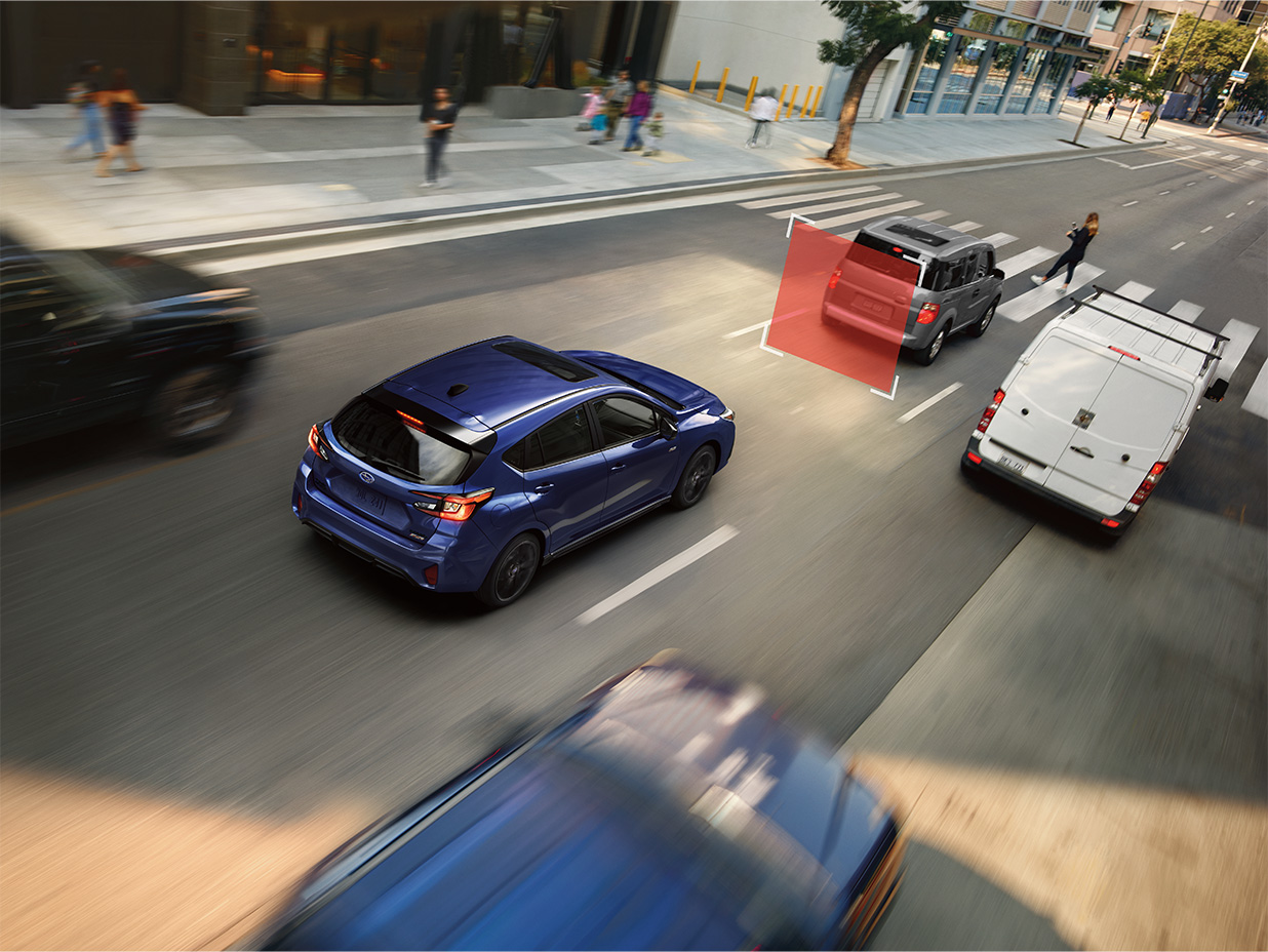 A blue Subaru hatchback driving on a city street highlights a vehicle ahead with a red safety system graphic.