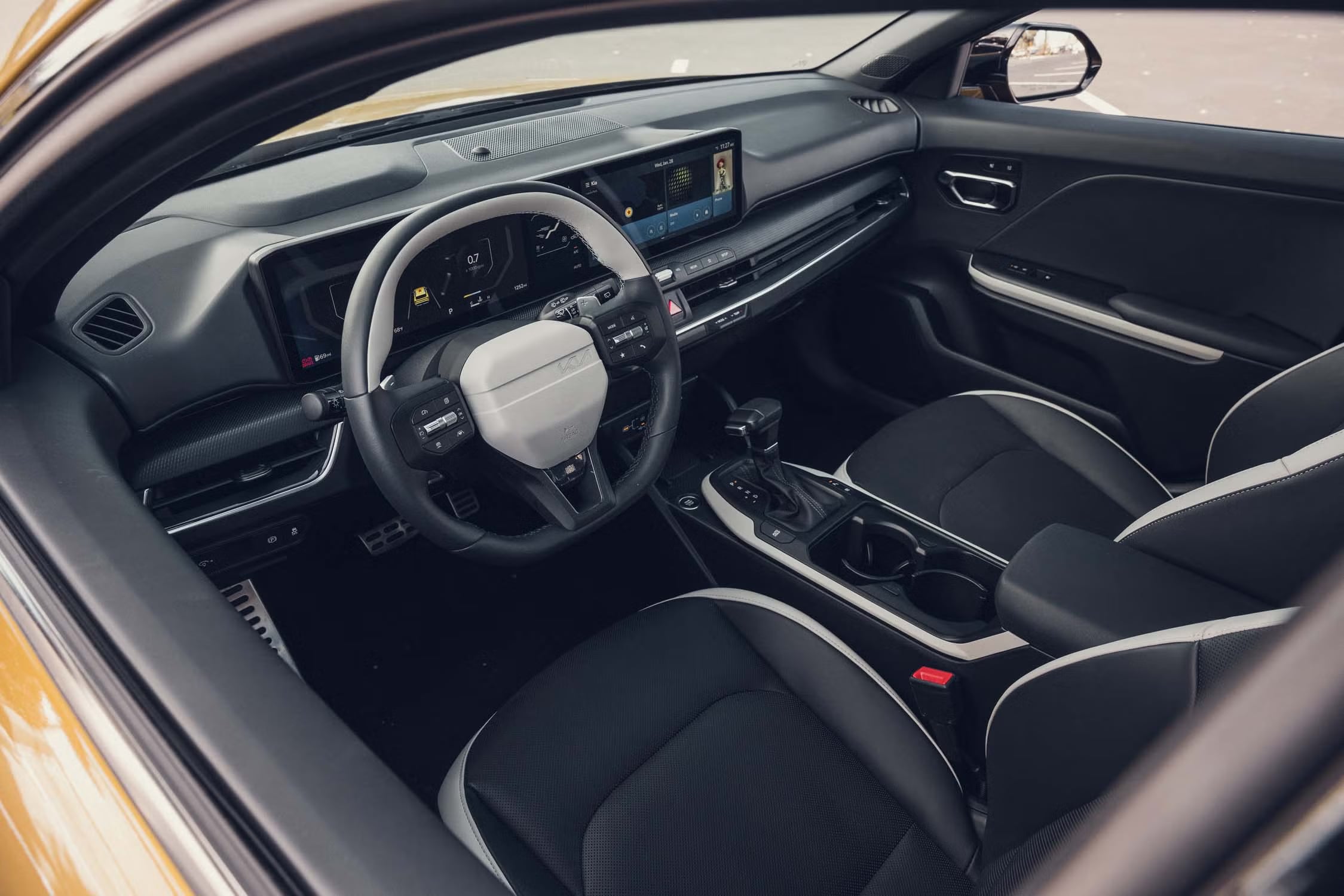 Interior of a Kia K4 showing the steering wheel, digital displays, dashboard, and front seats.