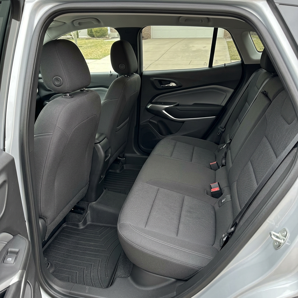Clean dark cloth rear seats and custom rubber floor mats inside a silver vehicle. (Representative image for illustration purposes only. Actual vehicle may vary based on trim and configuration.)