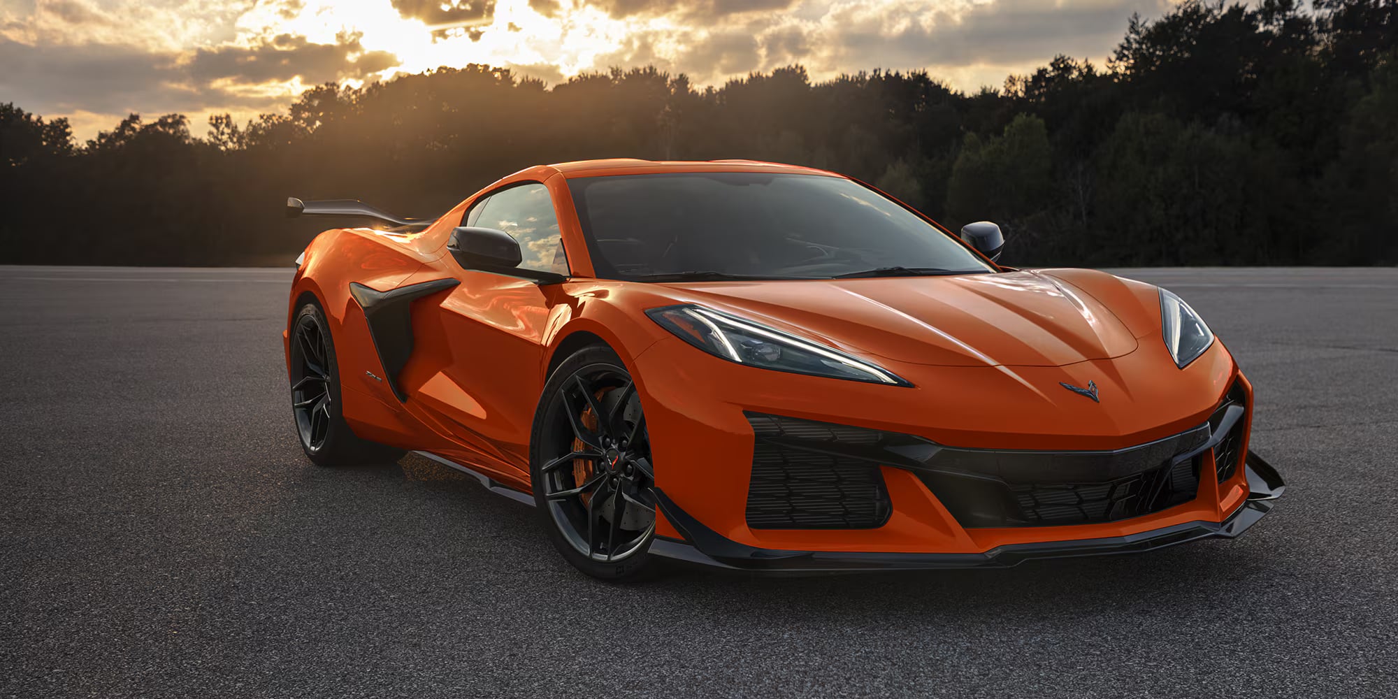 Bright orange Chevrolet Corvette Z06 parked on an asphalt track during sunset.