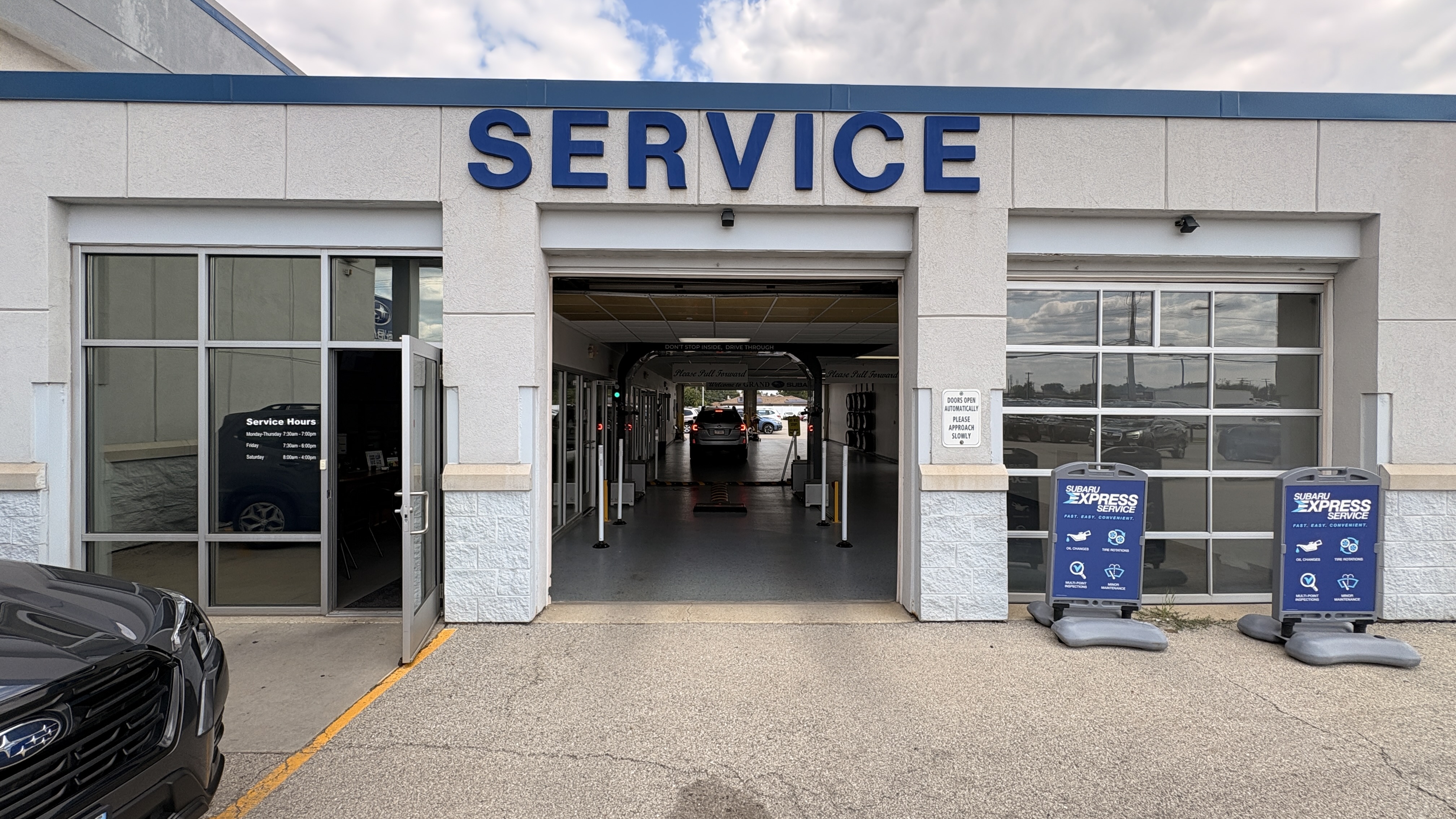 Entrance of a Subaru dealership service center with a drive-through bay and Subaru Express Service signs.