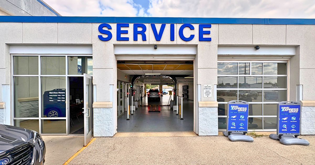 Drive-thru entrance to a Subaru dealership auto service center with a blue SERVICE sign overhead.