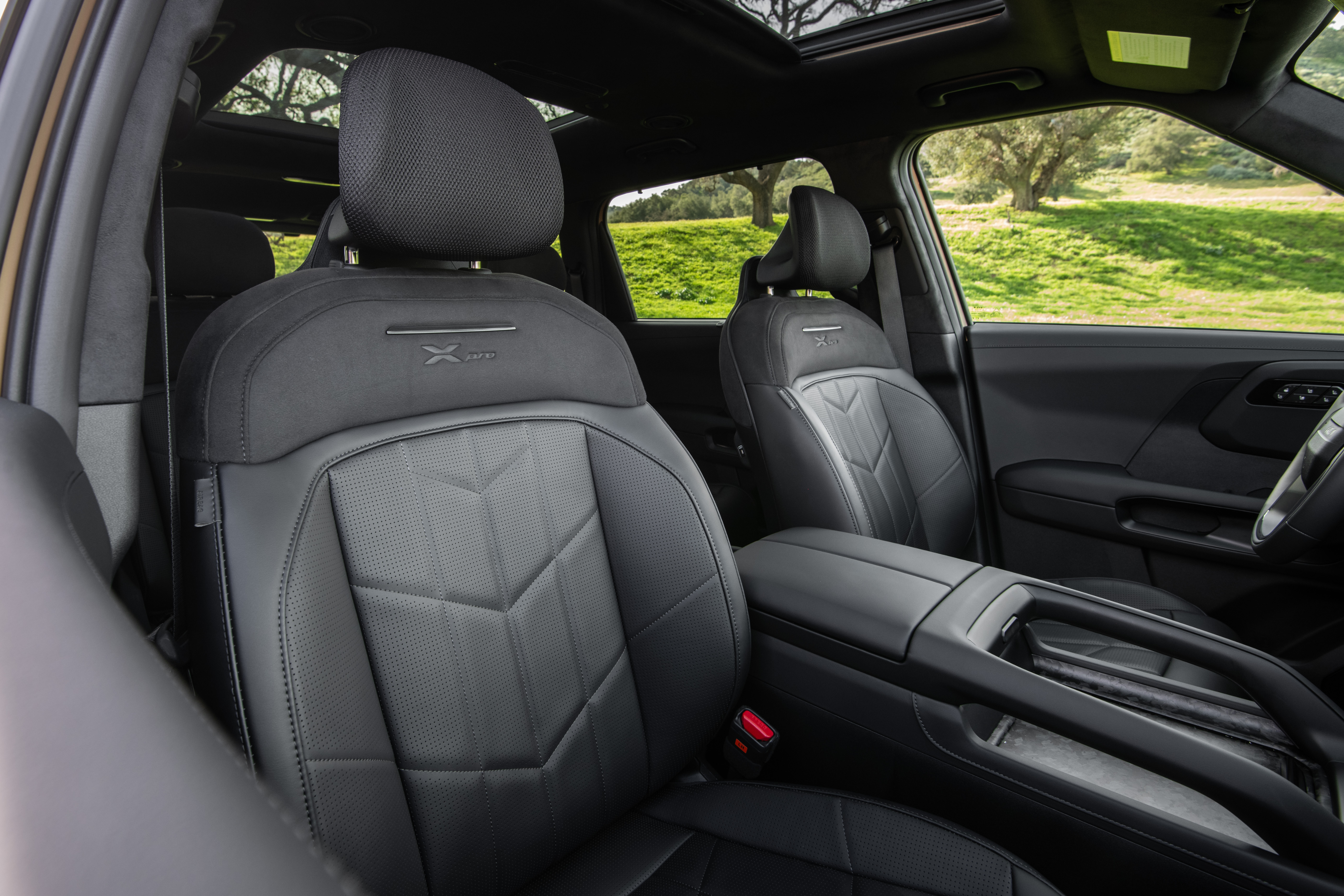 Interior view of black leather seats in a Kia Telluride X-Pro with green hills visible through the window.