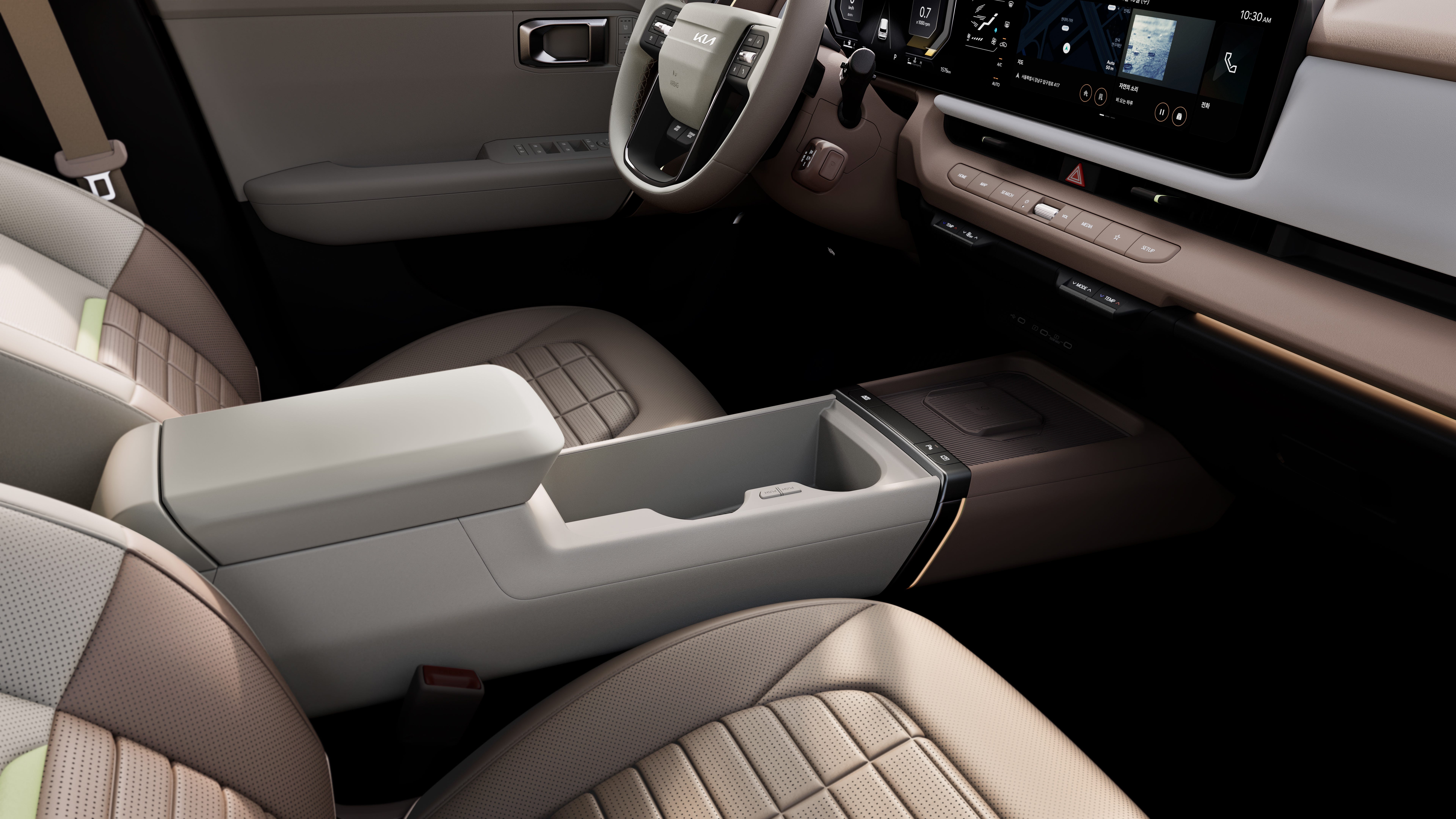 Front interior of a Kia vehicle featuring beige leather seats, center console storage, steering wheel, and digital screen.