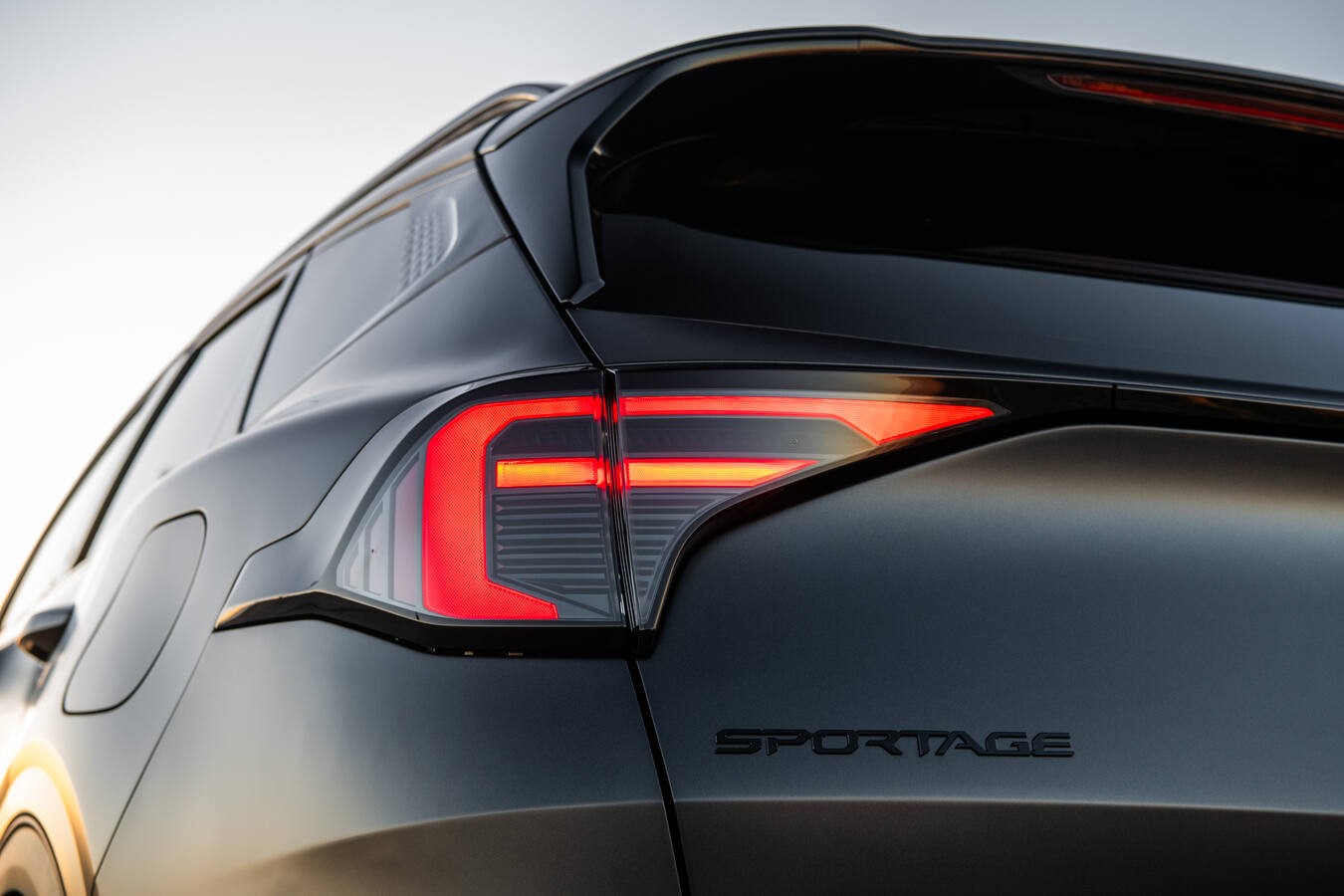 Close-up of the illuminated Kia Sportage taillight and dark badging.
