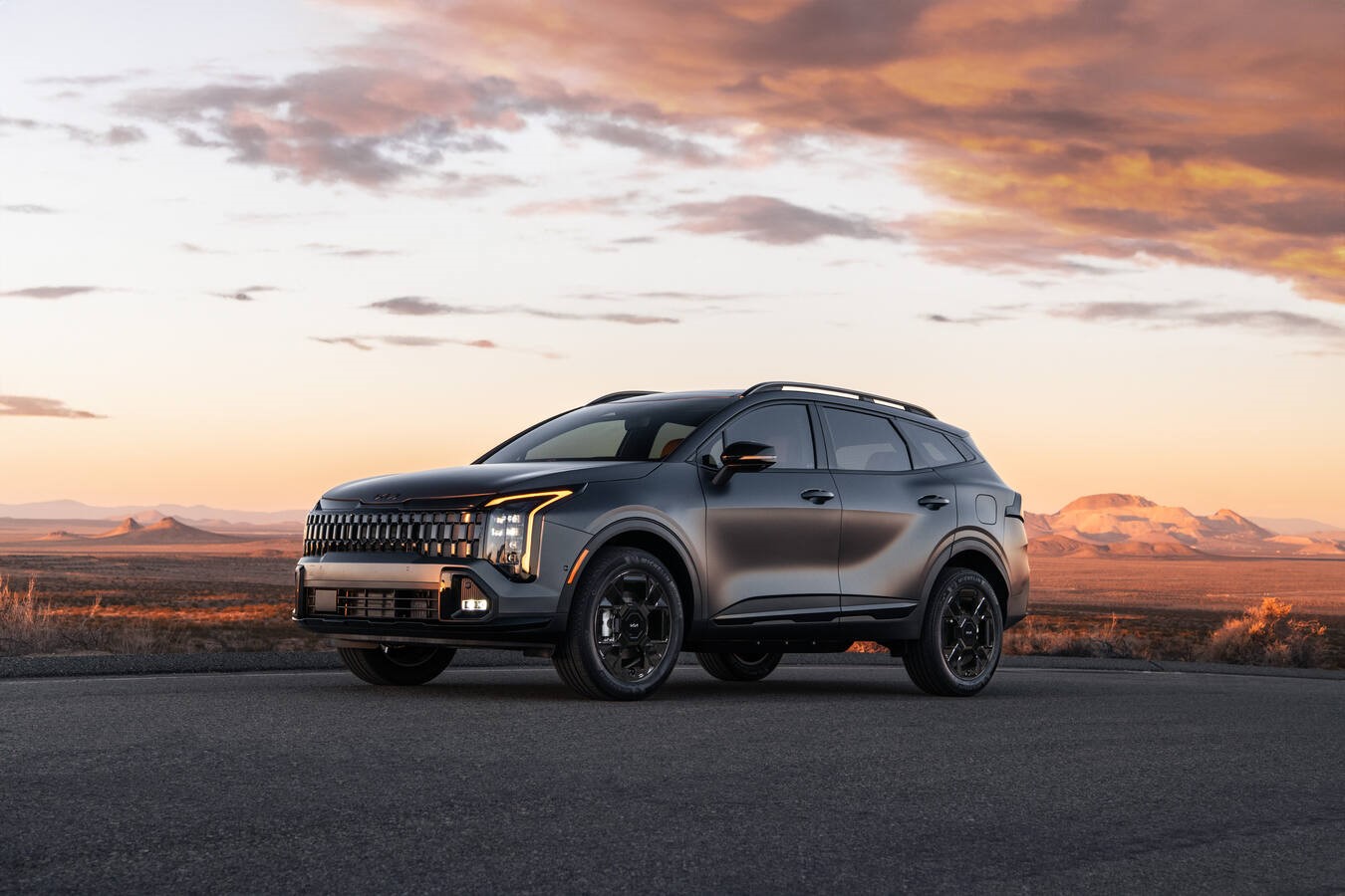 Dark gray Kia Sportage parked on a paved road at sunset.