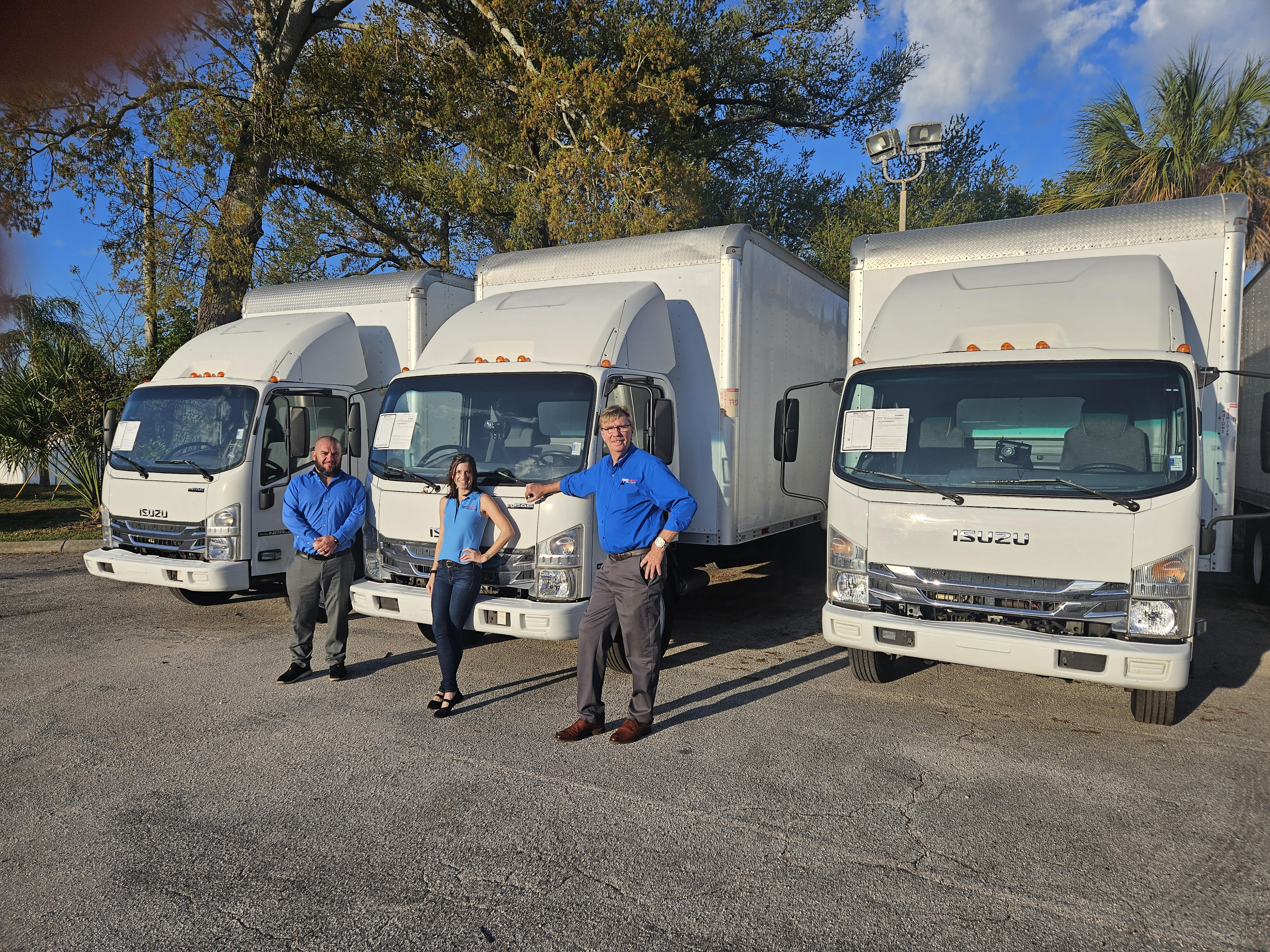 A fleet of Isuzu NPR trucks lined up ready for delivery at a commercial dealership