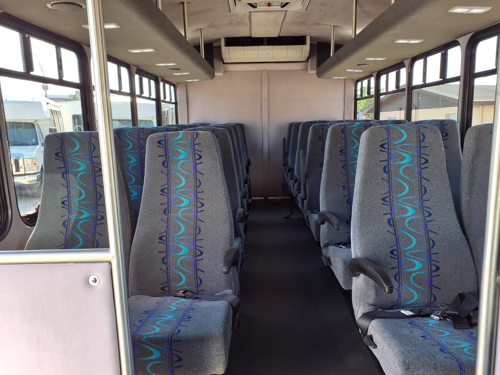 Interior view of a 15-passenger shuttle showing comfortable seating and wide center aisle.