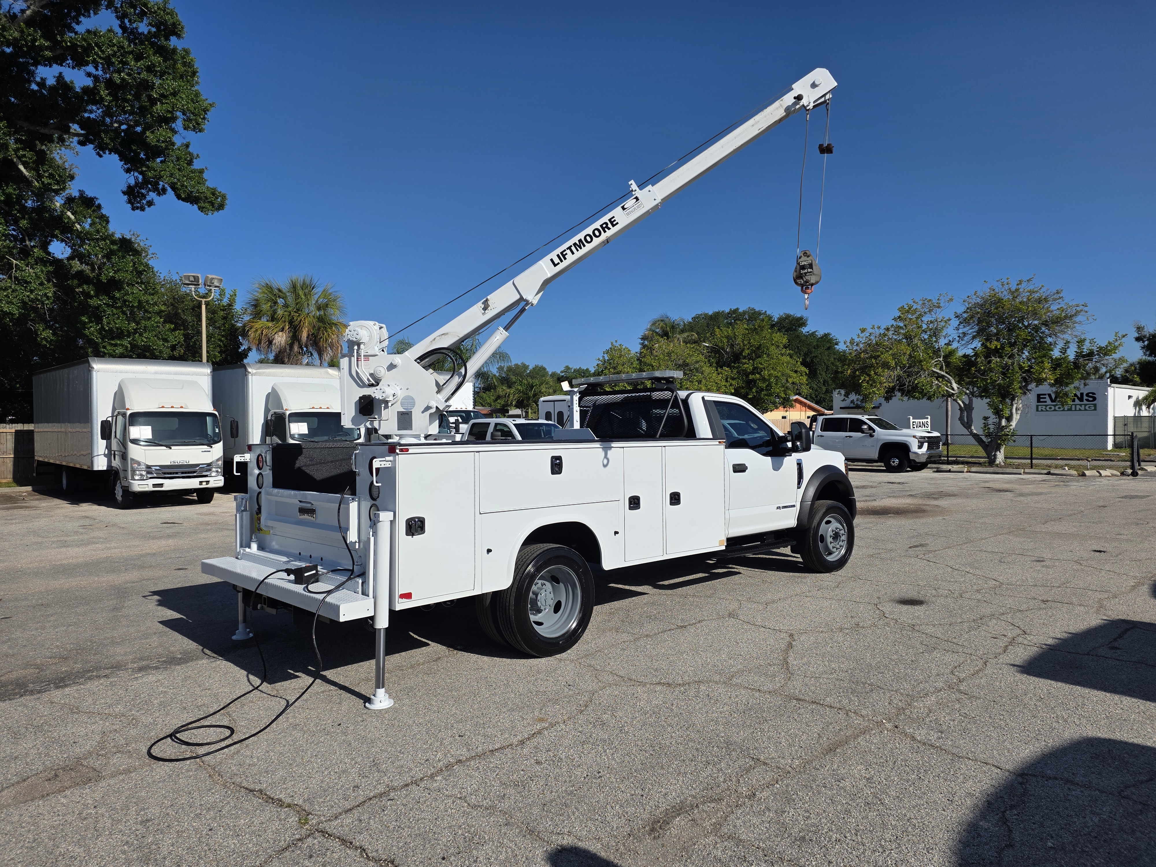 A close-up view of hydraulic cylinders and hoses on a service truck crane being inspected for leaks.