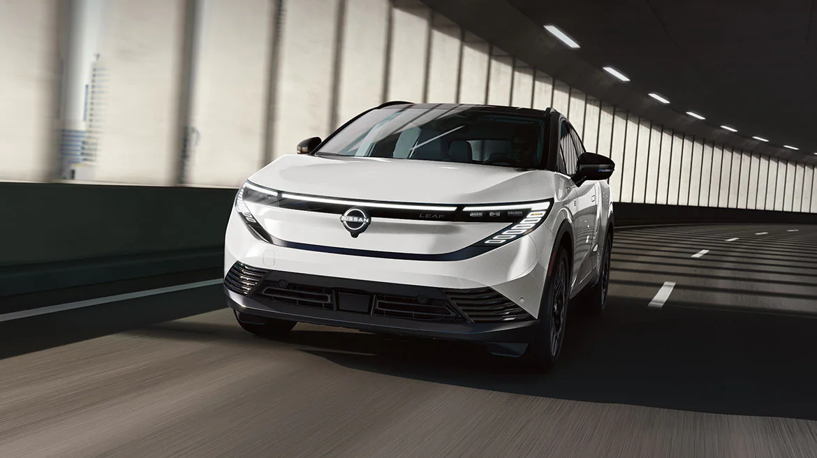A sleek 2026 Nissan LEAF in a modern crossover body style driving through a contemporary urban environment.