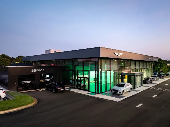 Genesis dealership exterior with cars and service entrance at dusk.