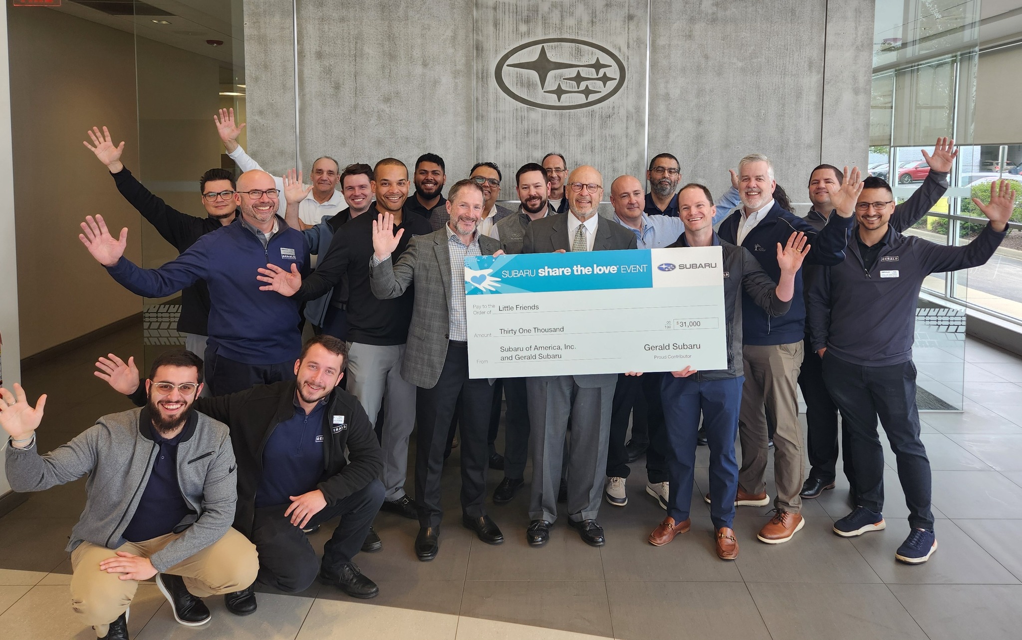 A group of employees at Gerald Subaru holding a large ceremonial check for $31,000 made out to Little Friends.