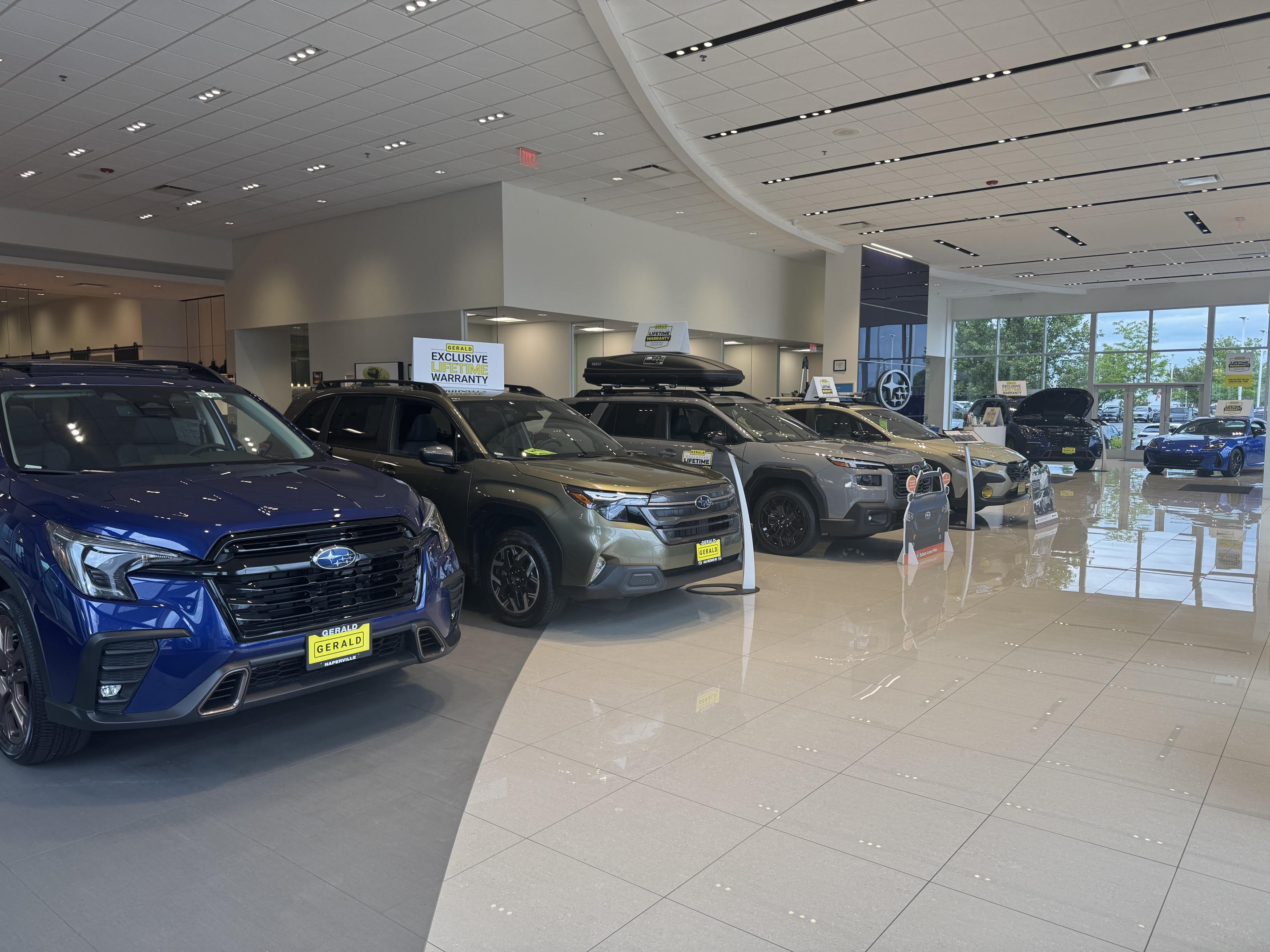 Row of new Subaru SUVs and cars inside a brightly lit Gerald dealership showroom.