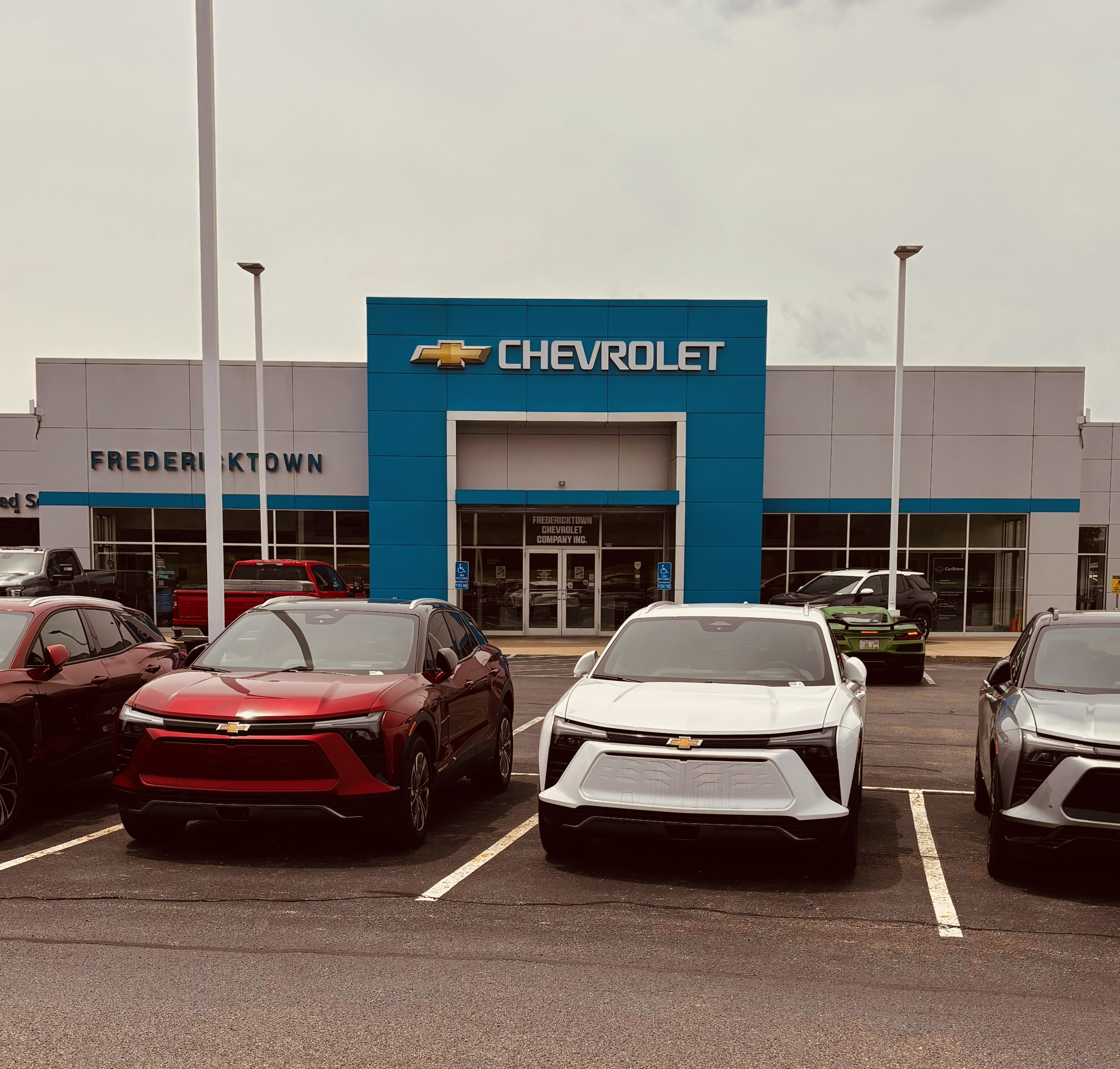 Front view of Fredericktown Chevrolet dealership with new red, white, and grey Blazer EVs parked in front.