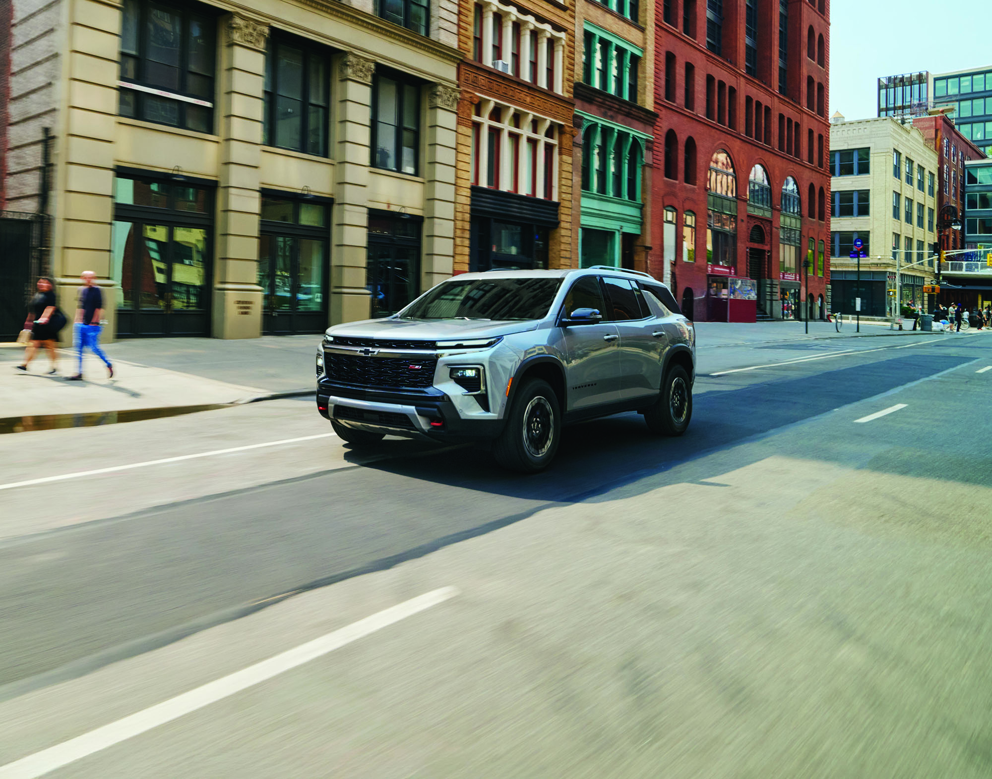 Silver Chevrolet Traverse Z71 driving along an urban street lined with historic brick buildings.