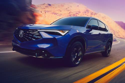 A blue Acura SUV driving on a winding mountain road at dusk.