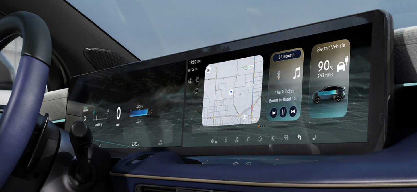 A wide, curved digital dashboard display in a modern electric vehicle showing navigation, music, and battery status.