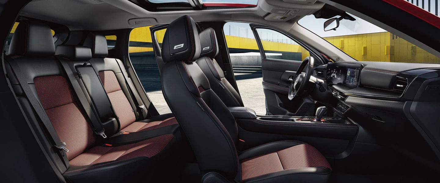 Interior view of a modern car with black and red upholstery, Bose headrest speakers, and a digital dashboard.