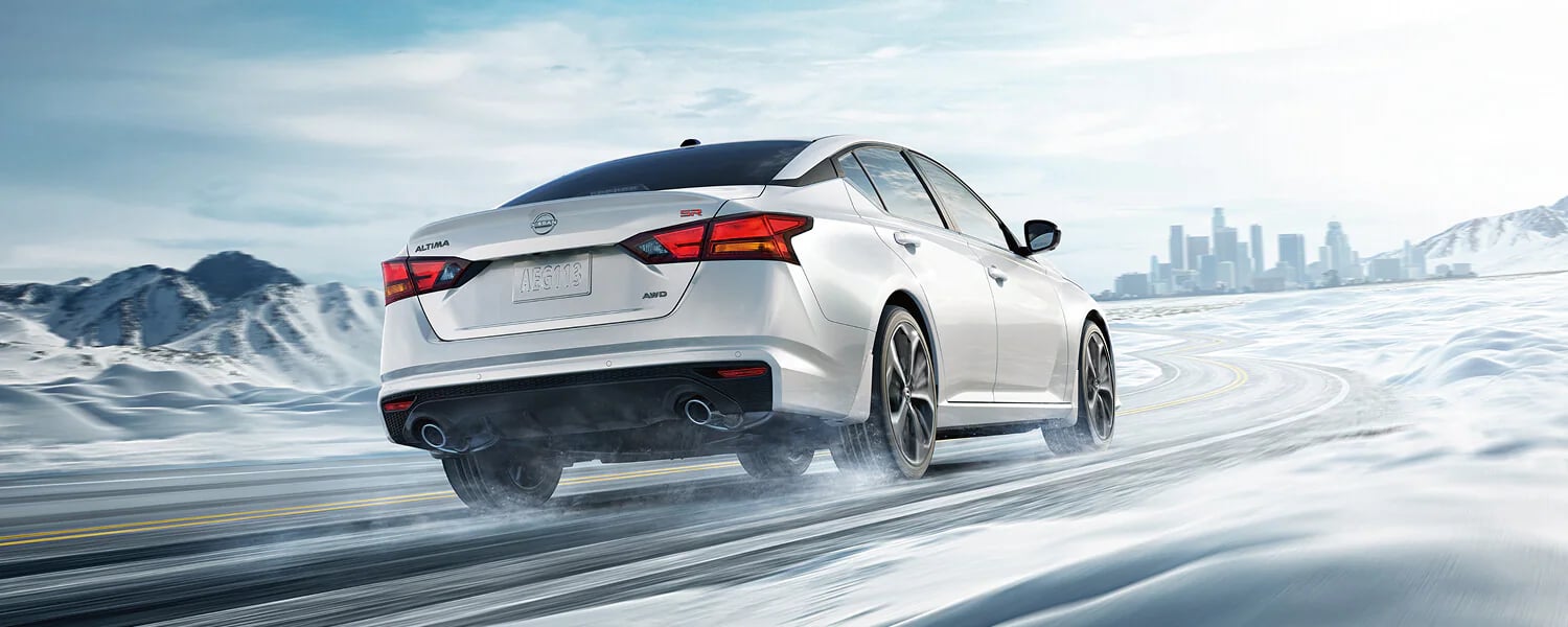 White Nissan Altima SR AWD driving on a snowy road