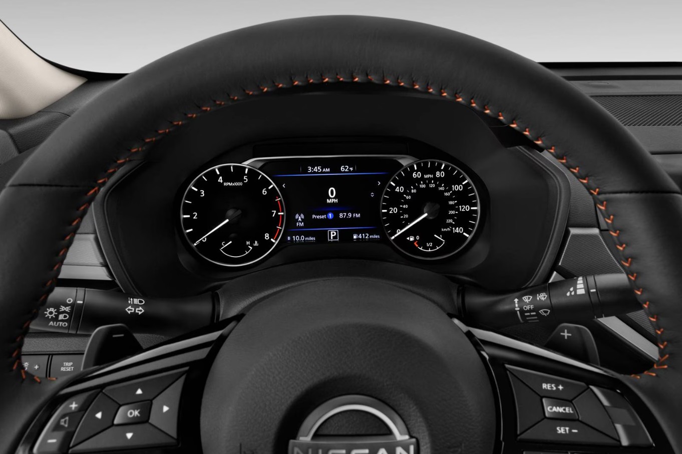 Dashboard and steering wheel of a Nissan vehicle featuring a digital instrument cluster and orange stitching.
