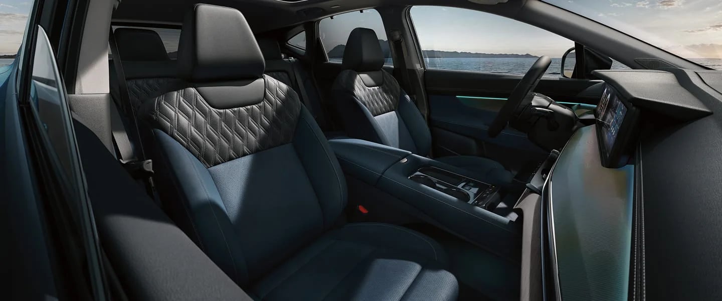 Modern car interior featuring two-tone blue and dark gray quilted leather seats and a coastal view.