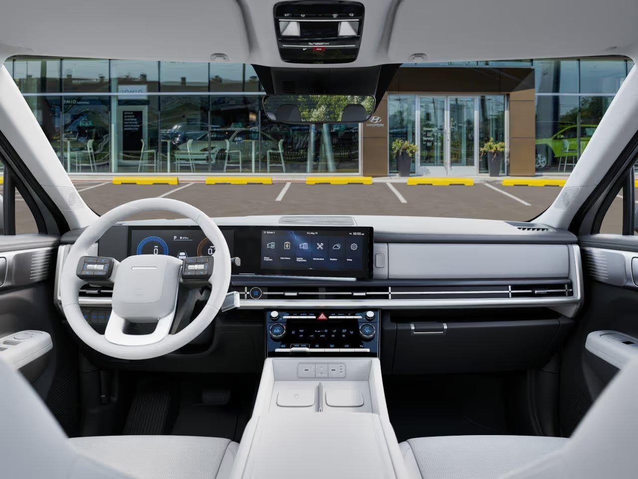 View from inside a modern car facing the dashboard, white steering wheel, digital displays, and windshield.