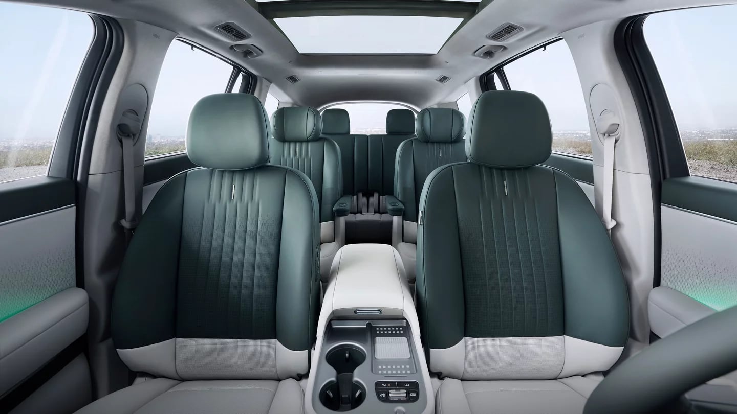 Wide interior view of a modern SUV showing three rows of green and light gray leather seating.