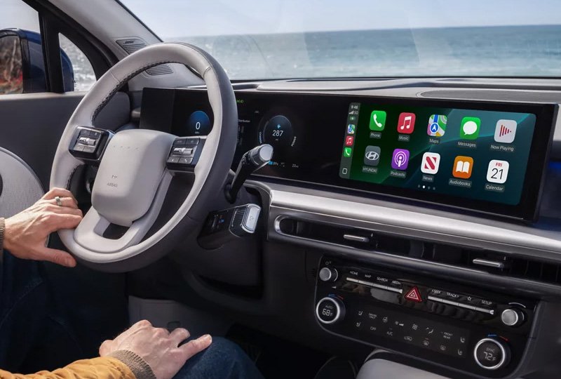 Driver seat view of a modern Hyundai dashboard featuring a dual digital screen setup, steering wheel, and center console.