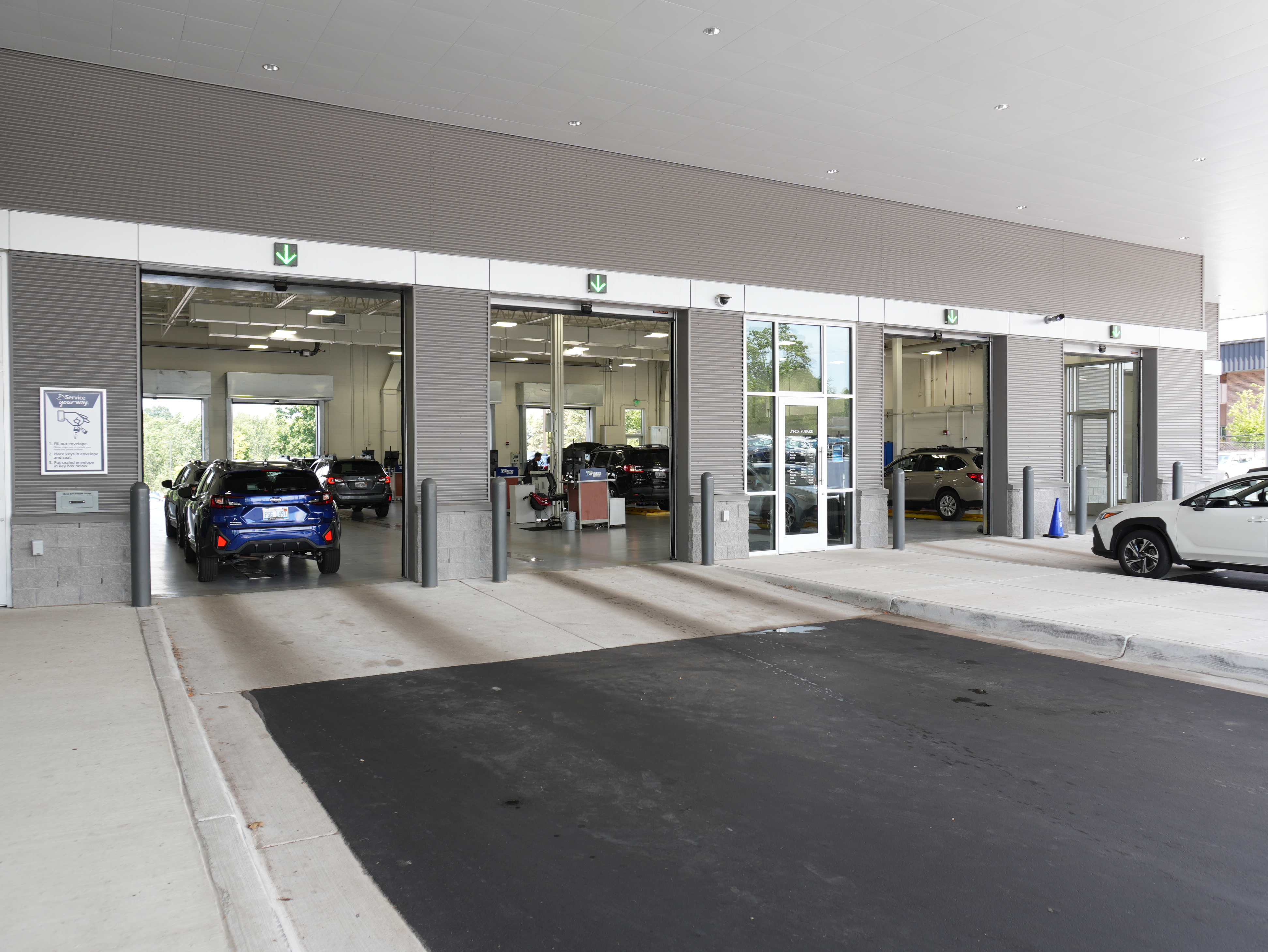 Multiple service bay entrances at a Subaru dealership with cars parked inside.