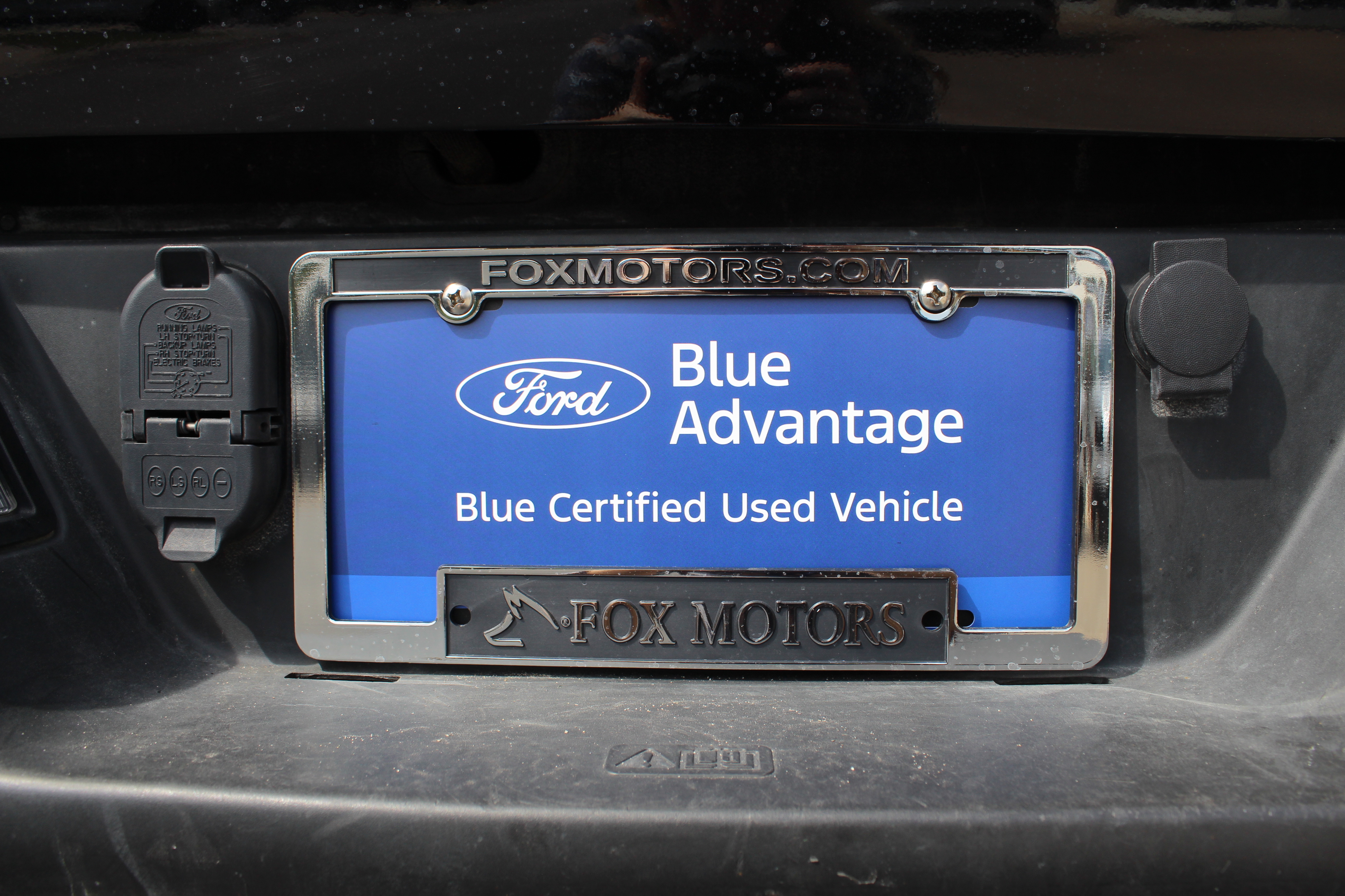 Ford Blue Advantage certified used vehicle license plate frame from Fox Motors on a black vehicle.