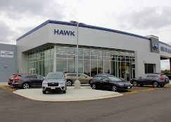 Exterior of Hawk Subaru dealership with multiple cars parked in the front lot on an overcast day.