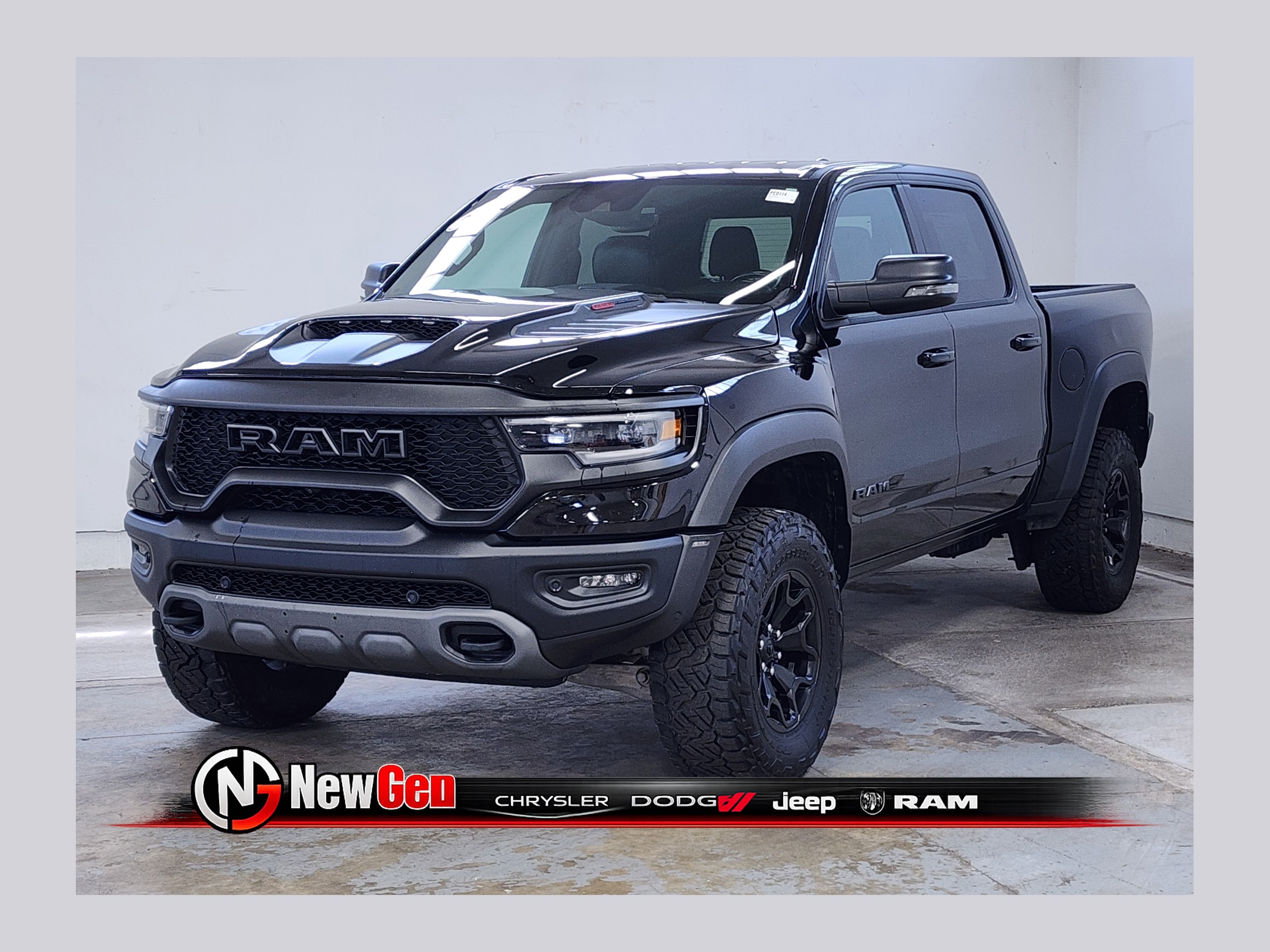 Black Ram 1500 TRX pickup truck with rugged off-road tires parked in a dealership showroom.