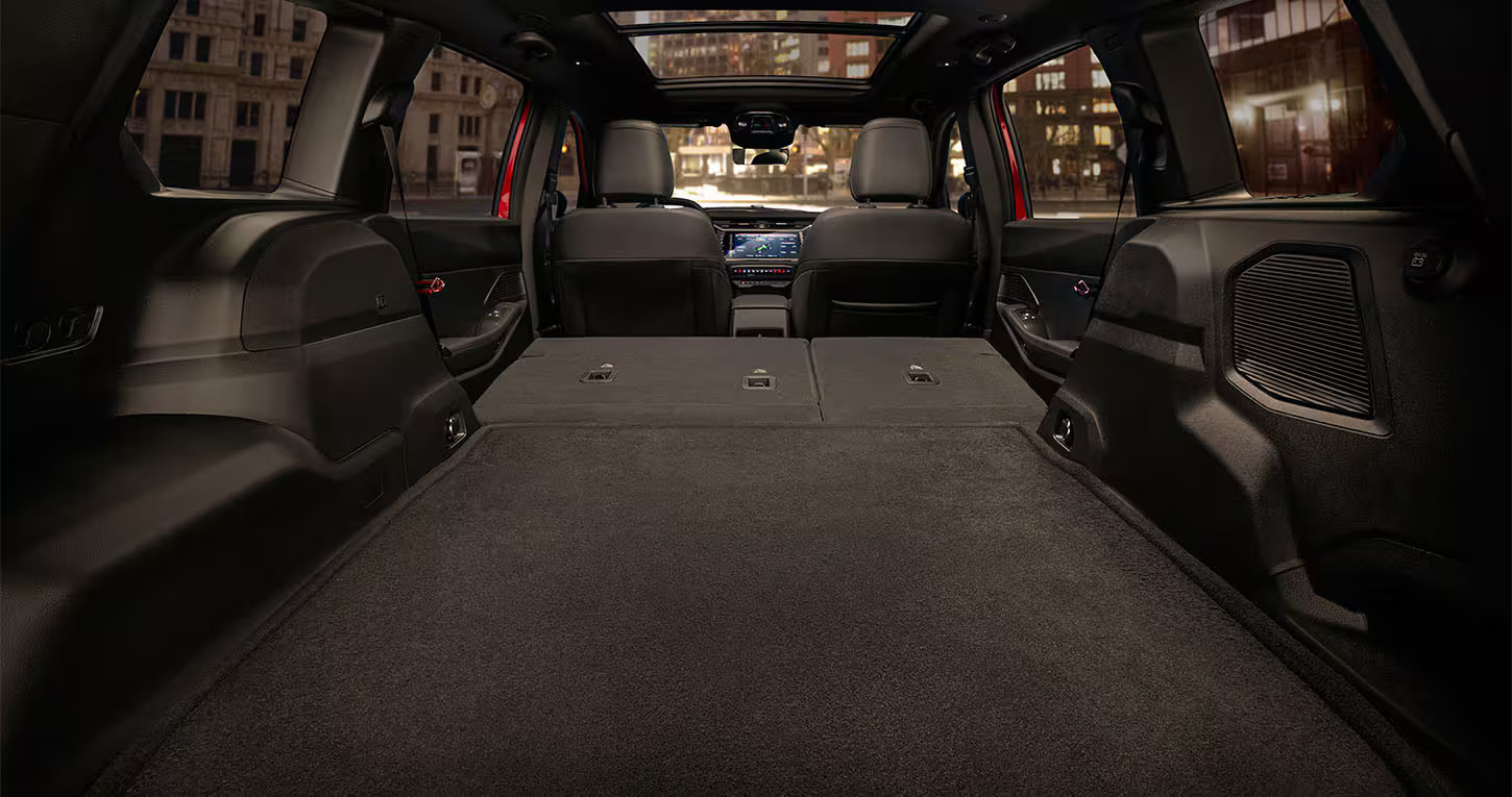 Interior view of an SUV trunk with rear seats folded flat, creating a large carpeted cargo space at night.