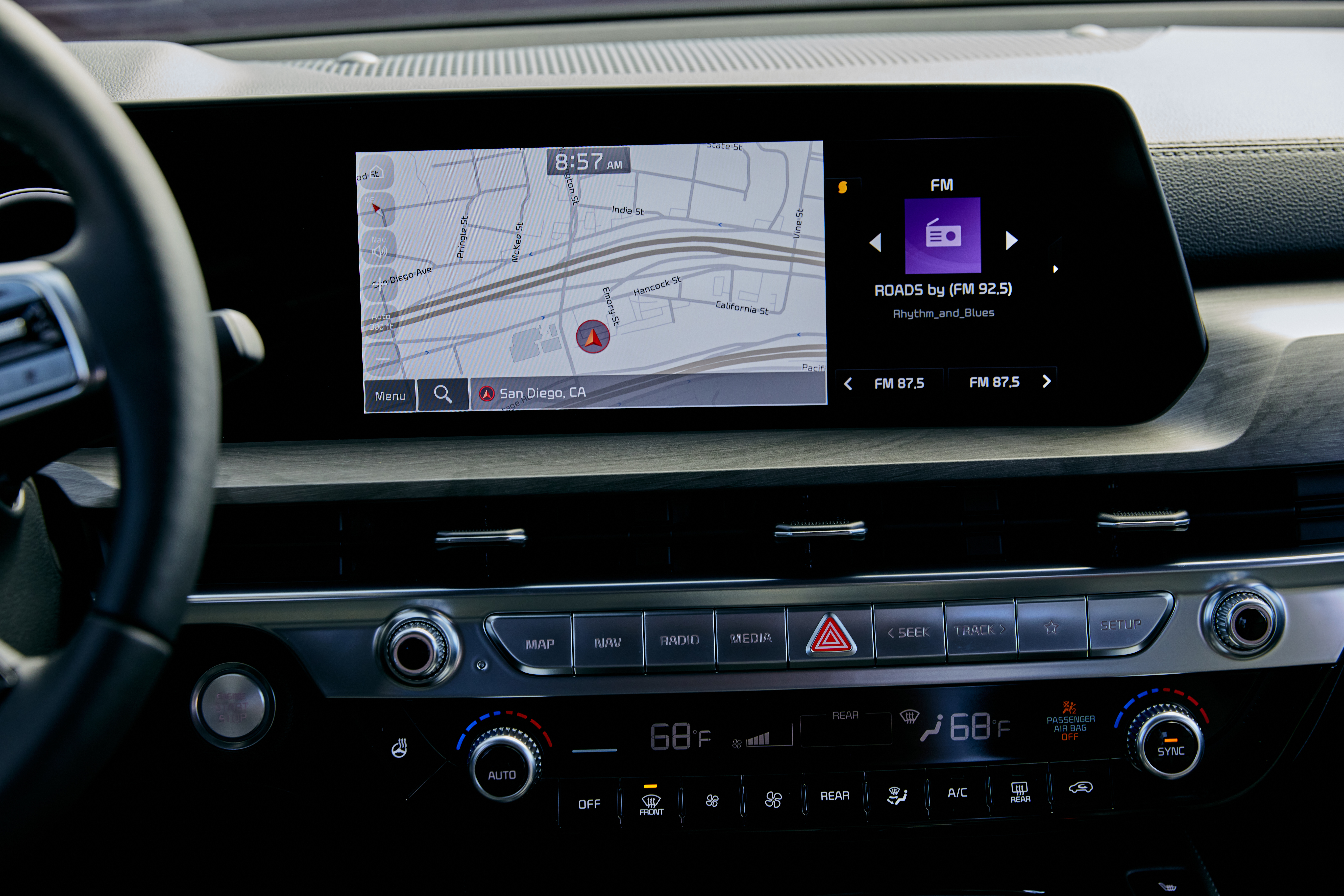 Modern car dashboard with infotainment screen displaying a map and radio controls above climate settings.