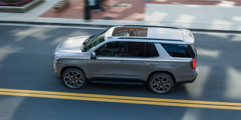 High-angle view of a modern silver SUV driving on a city street with double yellow lines.