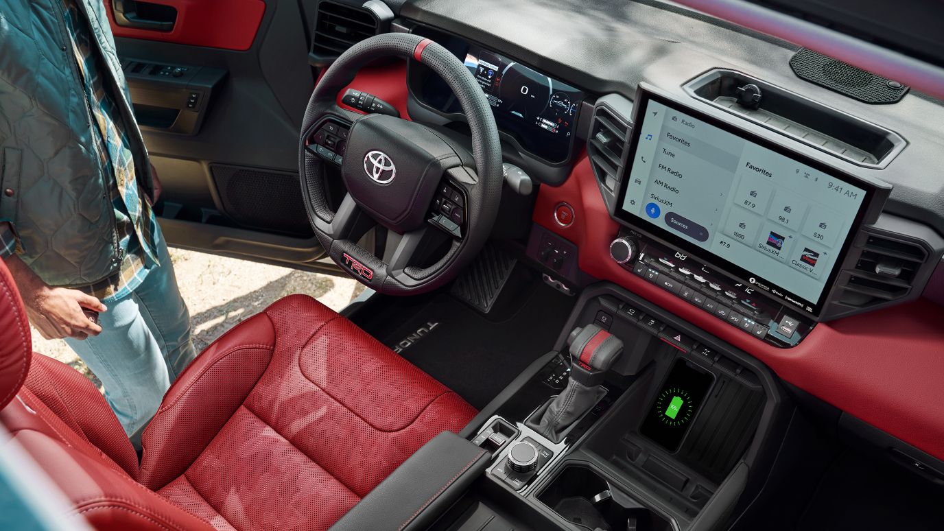 High-angle view of a Toyota Tundra's red leather interior, digital dashboard, and center console.