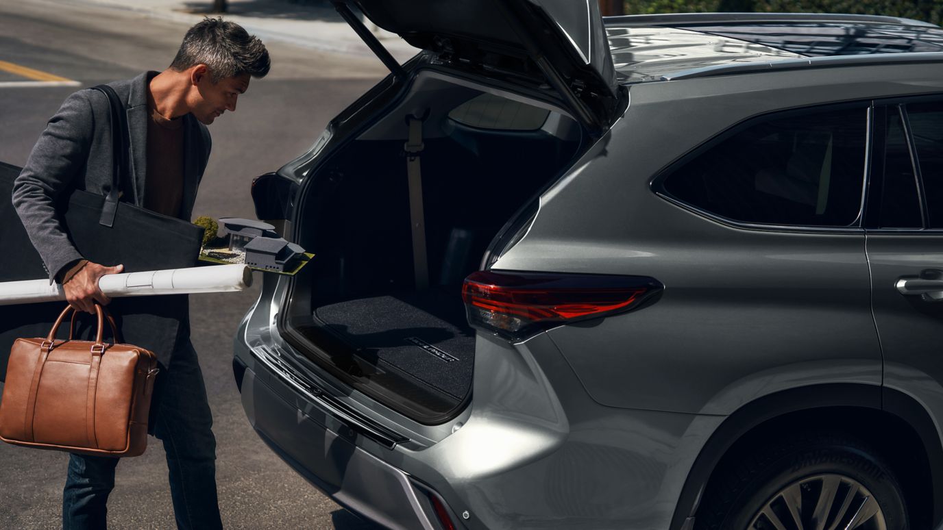 A man putting some gear in a Toyota Highlander's trunk.