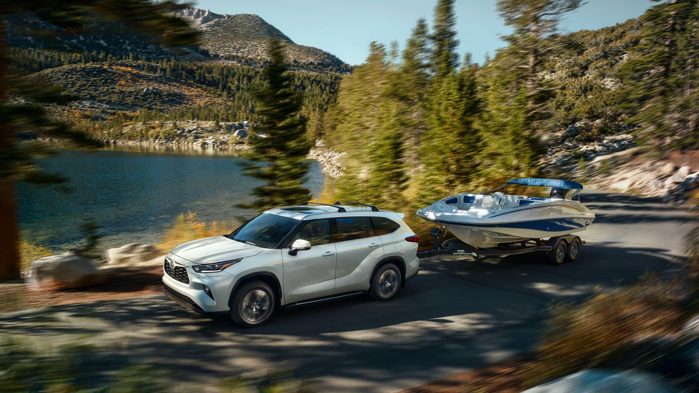 A white Toyota Highlander hauling a boat
