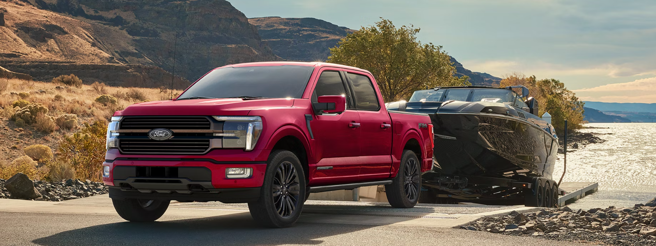 A red Ford F-150 backing a boat into a lake.