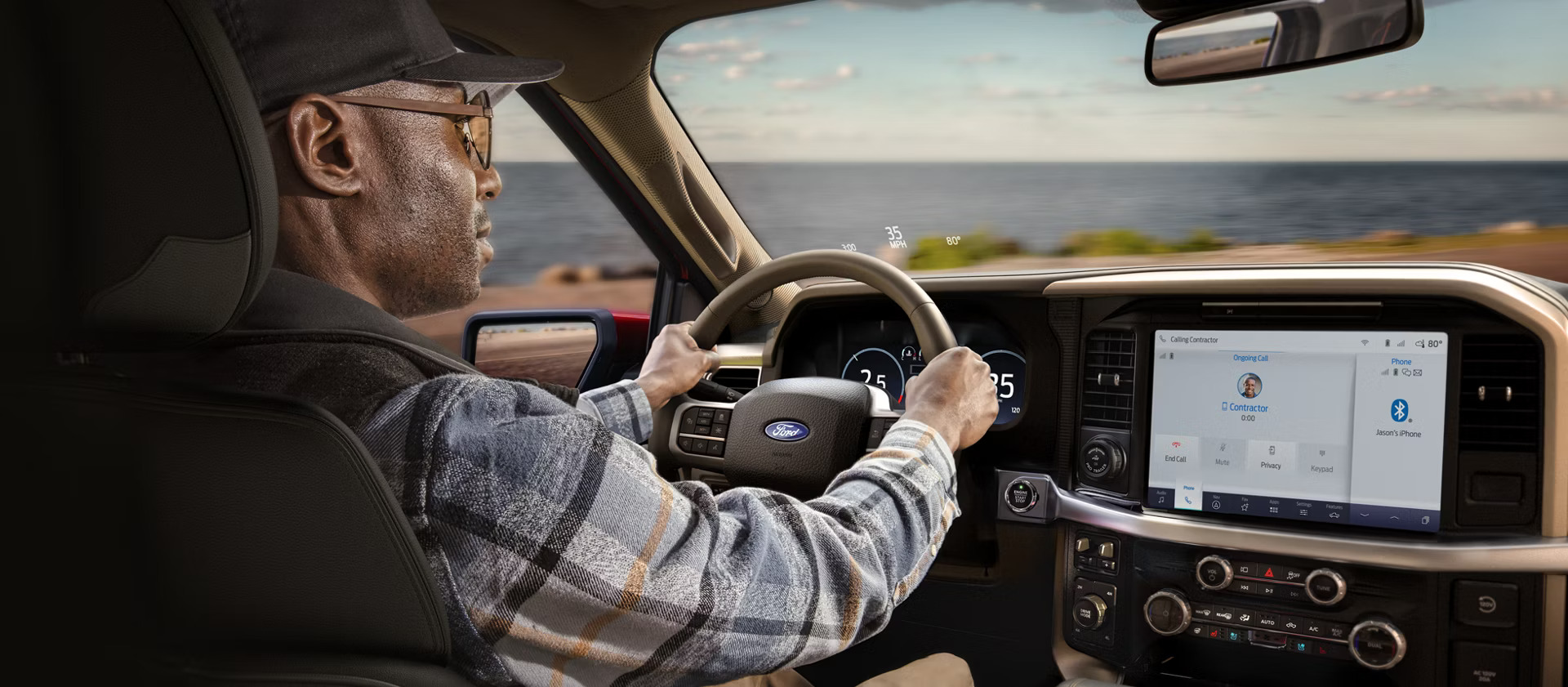 An interior view of a Ford F-150 with a man driving and glancing at the vehicle's touchscreen.