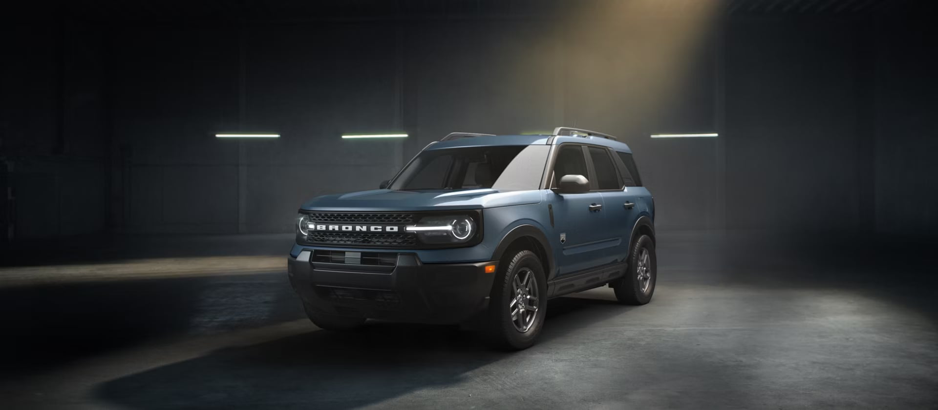 A blue Ford Bronco Sport in a dimly lit warehouse.