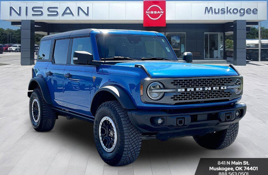 Blue Ford Bronco four-door SUV parked in front of a Nissan dealership in Muskogee, Oklahoma.