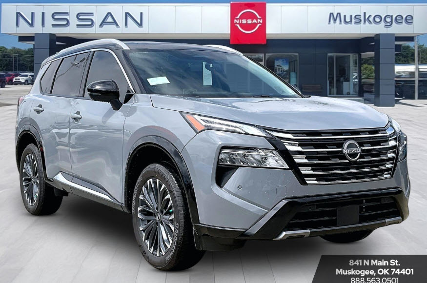 Grey Nissan Rogue with black roof parked in front of a Nissan Muskogee dealership.