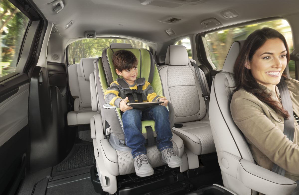 Child in car seat with tablet while mother drives.