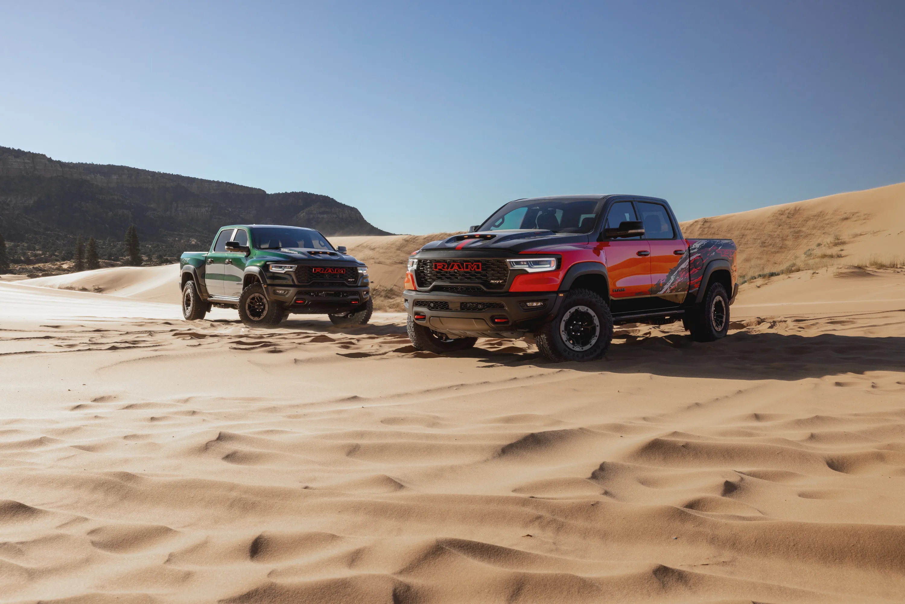 Red and green Ram TRX trucks in a desert landscape.
